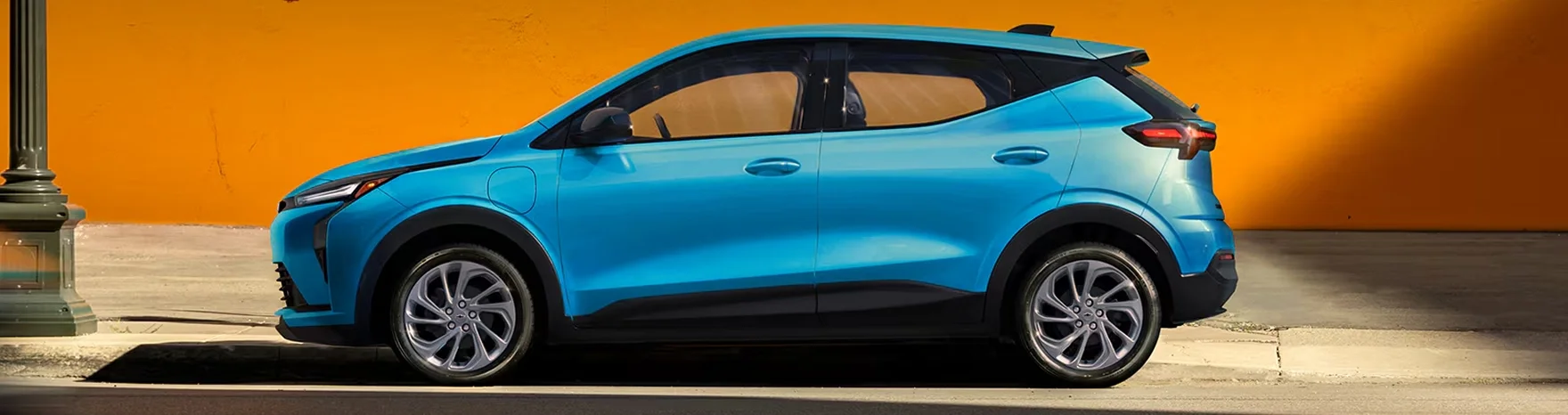 Side profile of the 2027 Chevrolet Bolt in blue showing the sleek silhouette and 17-inch aluminum wheels