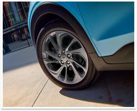 Close-up of the 2027 Chevrolet Bolt 17-inch aluminum wheel and front fender in blue