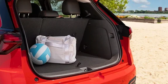 2027 Chevrolet Bolt open rear cargo area at a beach with a bag and volleyball inside