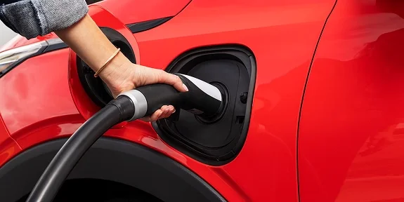 2027 Chevrolet Bolt plugged in at a public fast charging station during the day