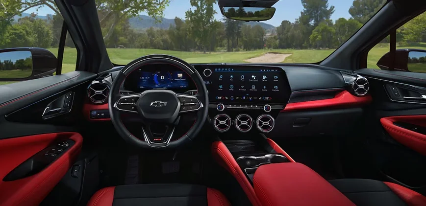 2027 Chevrolet Bolt RS cockpit view showing the steering wheel, dual screens, and red accent interior trim